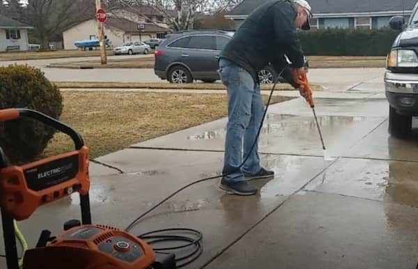 Man using generac gas pressure washer 3100 to clean concrete and own car