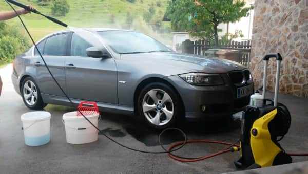 A man washes his BMW with a powerful pressure washer made by Karcher (K5 Premium model)
