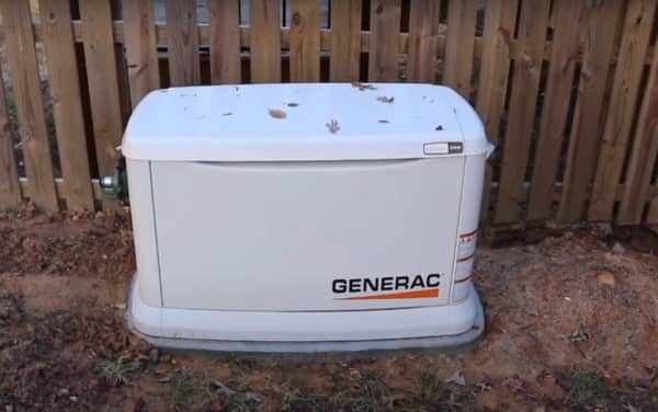 The backup generator was located near a wooden fence.
